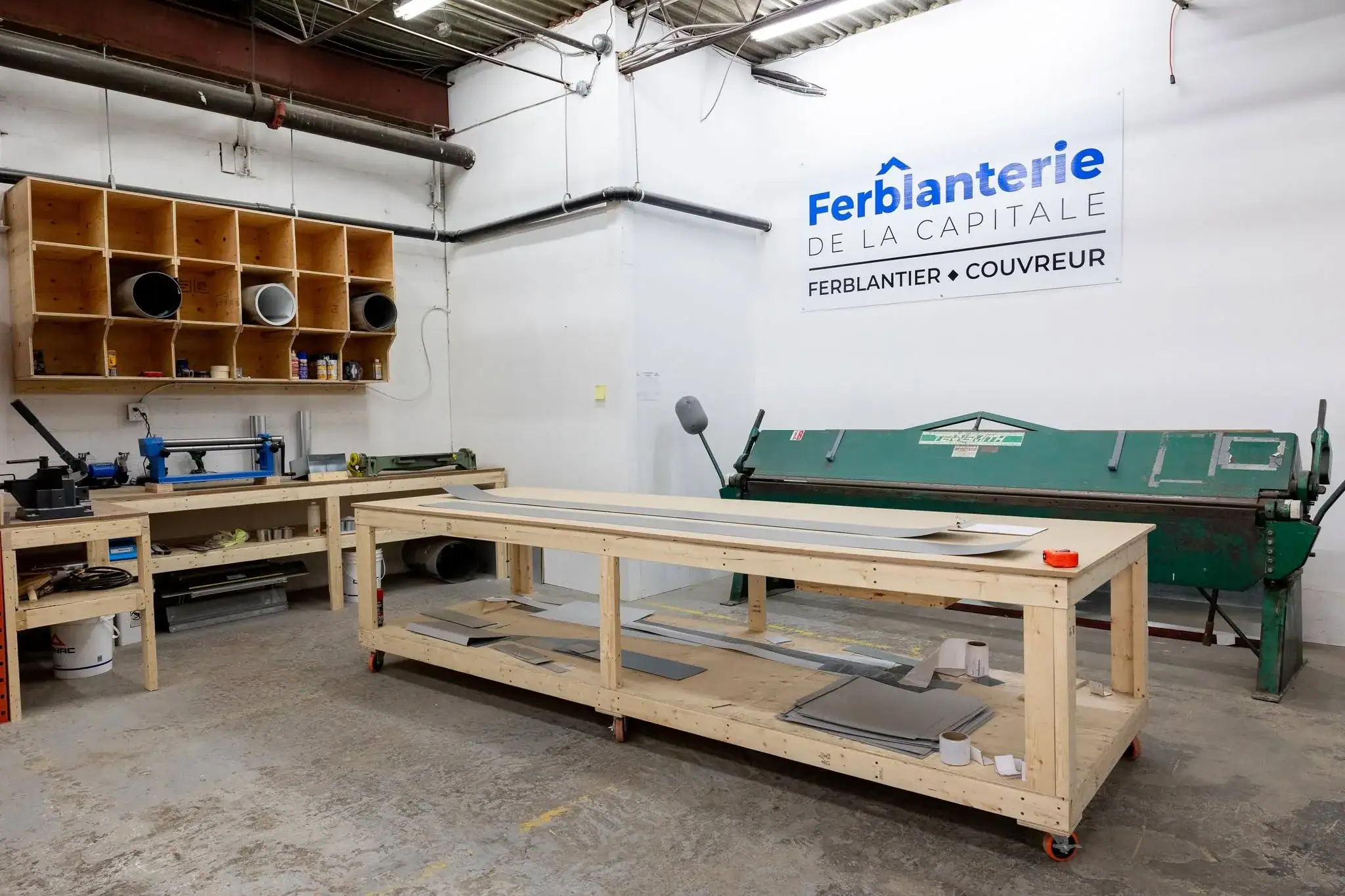 Atelier de la Ferblanterie de la Capitale : plieuse, établis et tôle prête à façonner